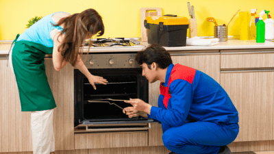 Broken Appliances housecleaner talking to contractor repairing oven